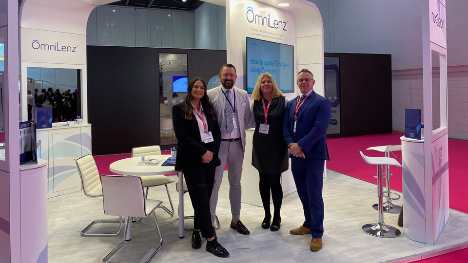 Stand at 100% Optical with four people standing in front of it