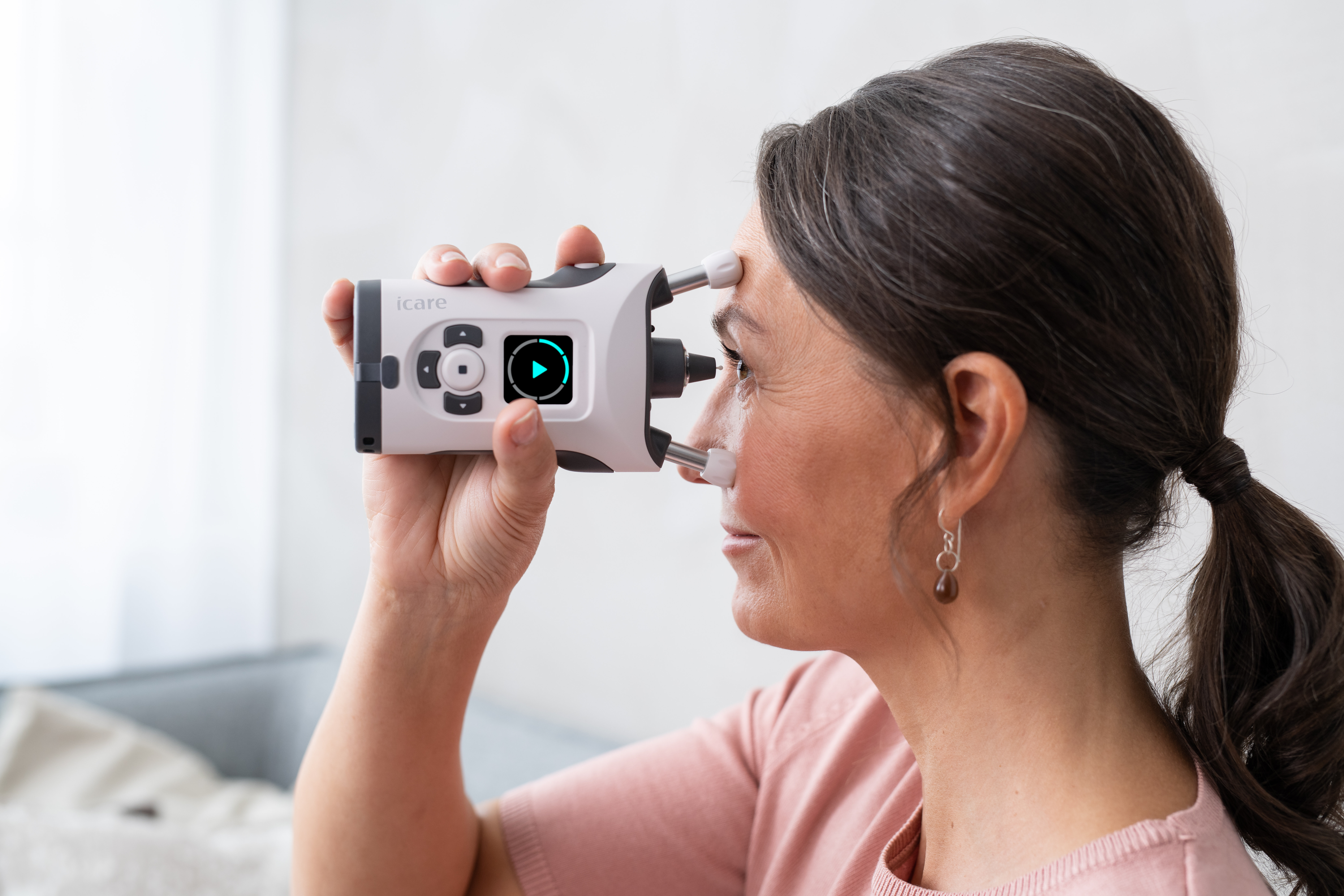 A woman takes her own intraocular pressure reading using the iCare Home2, a handheld tonometer1618394357wpdm_iCare_HOME2_woman_measuring2_HI
