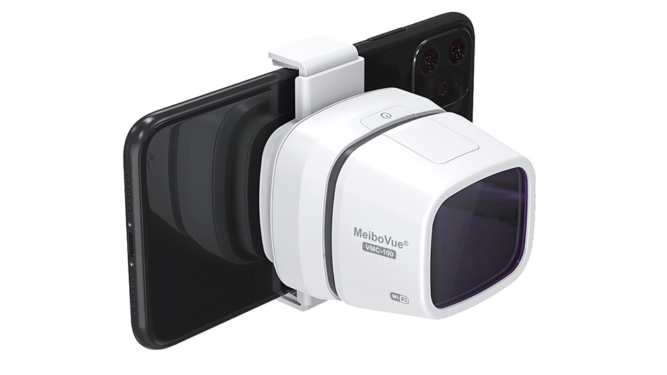 A smartphone is attached to a white device with a large screen/camera, on the side is printed ‘MeiboVue VMC-100