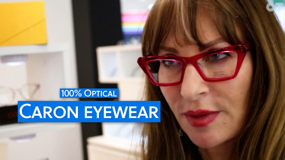 A still from an interview with Caron – she is wearing very angular translucent fluorescent pink glasses 