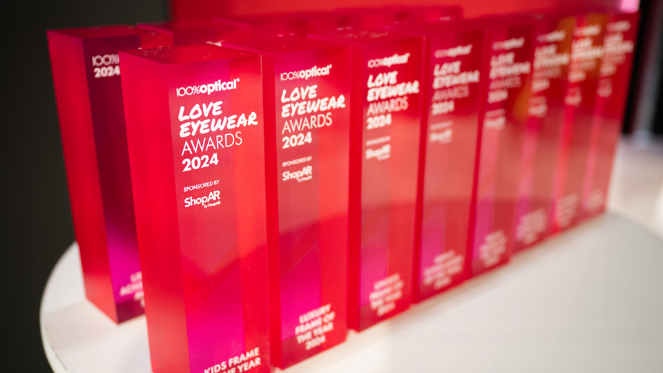 The Love Eyewear Awards, vivid pink-red glass rectangles, are arranged in a line  