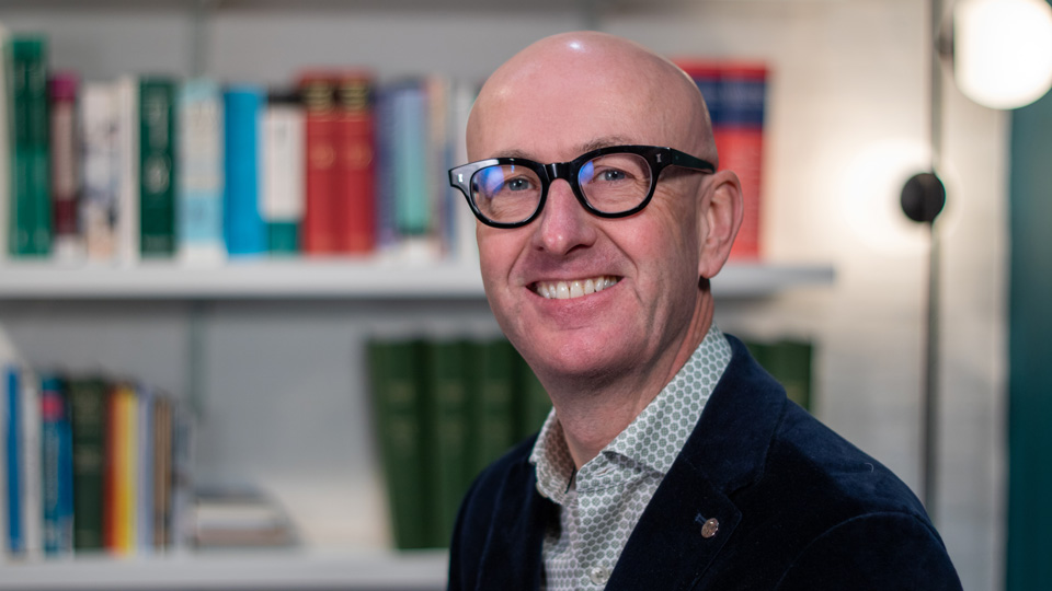Ian Beasley pictured, smiling, in a library