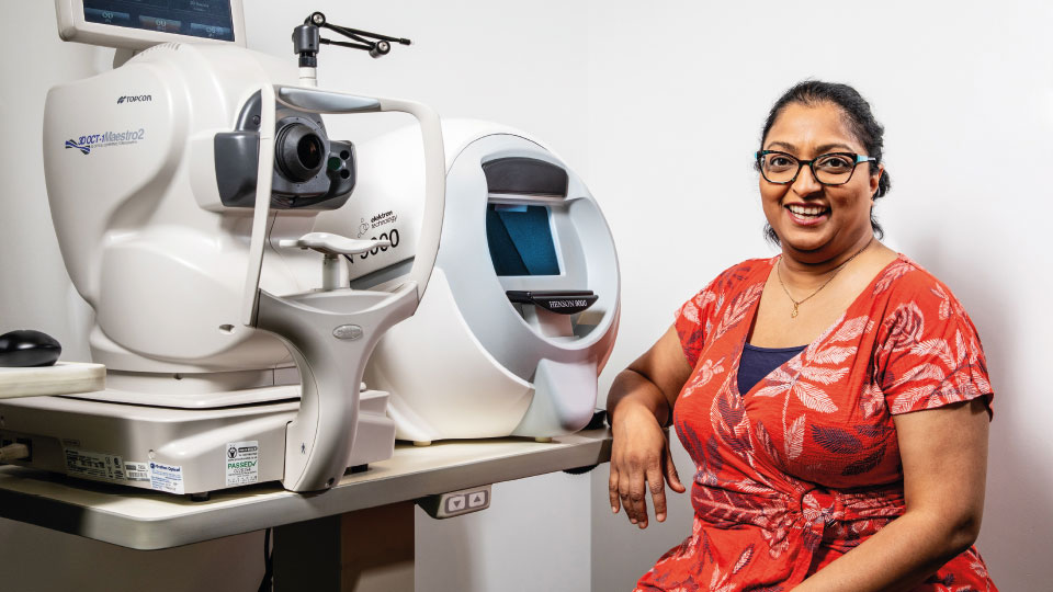 Bhavina Patel smiles next to an OCT machine