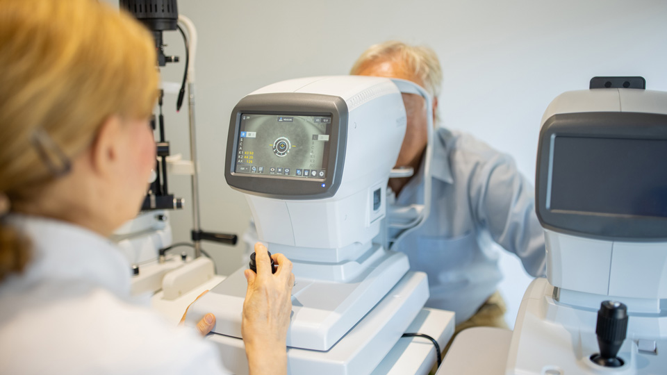 Elderly man having an eye exam with an OCT at optometrist's office