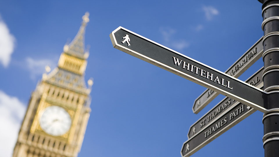  London sign directing towards Whitehall with Big Ben in background 