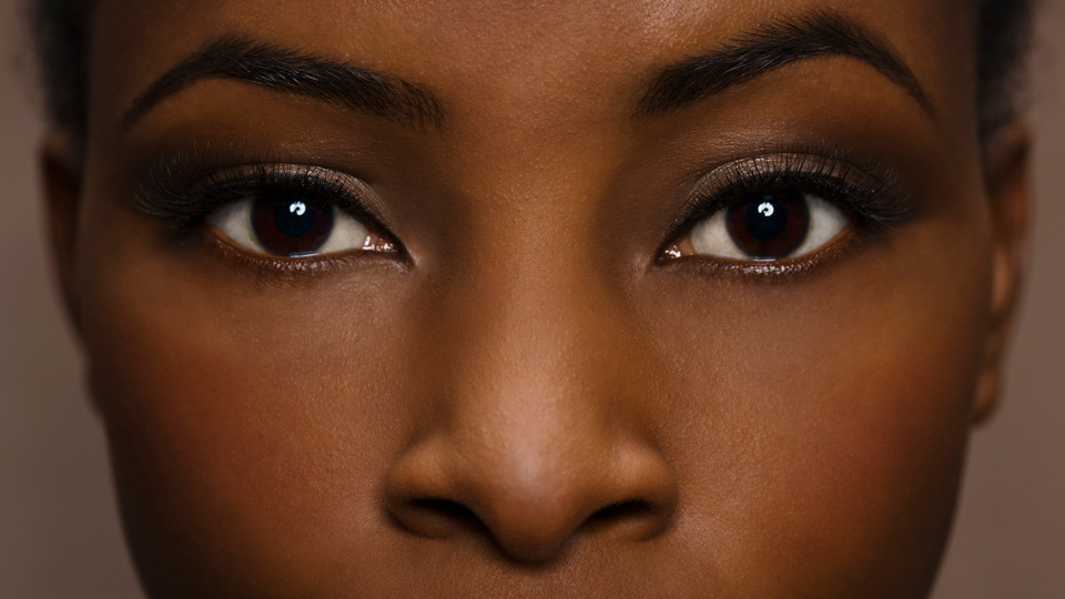 Young black woman with eyes wide open looks towards the camera  