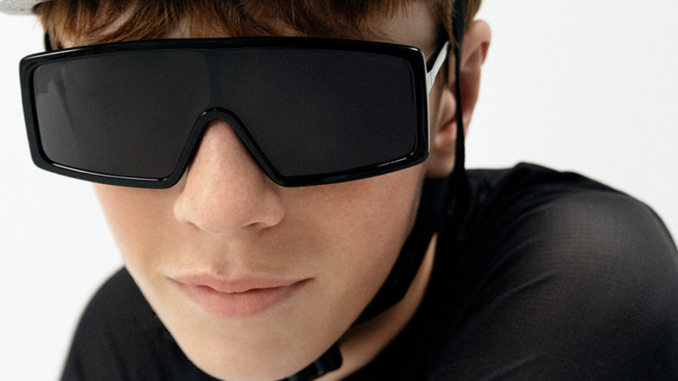 A teenage boy wears oversize black sunglasses with a white cycling helmet