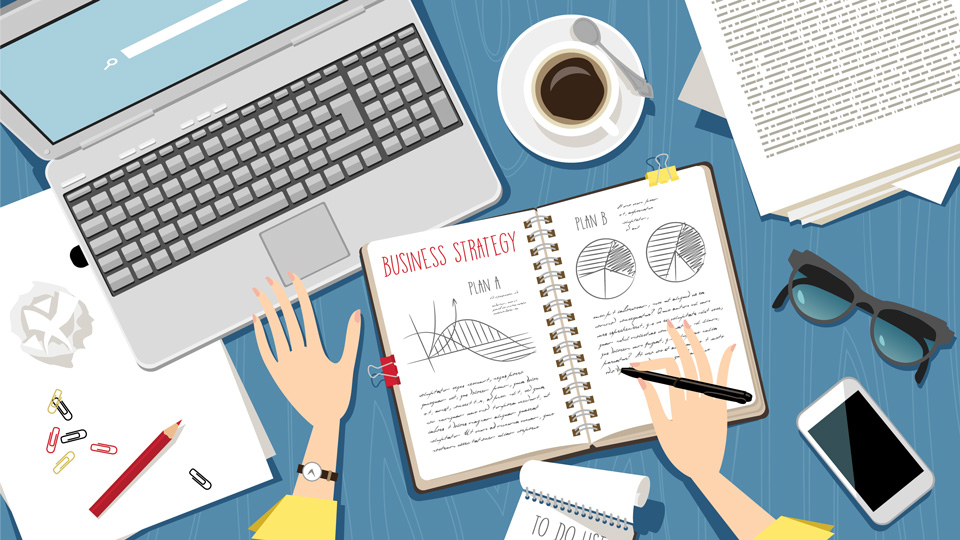 An illustration of hands making notes in a book with pie charts and data with a red headline reading ‘Business strategy’. A laptop and further papers, notepads, and stationery fill the desk