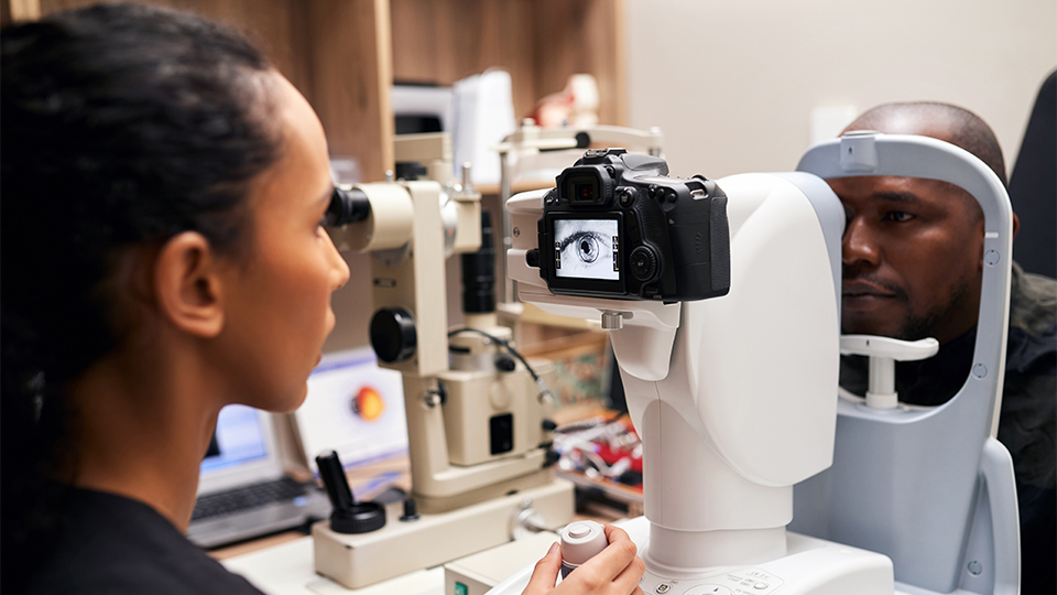 An optometrist performs an eye examination on a patient