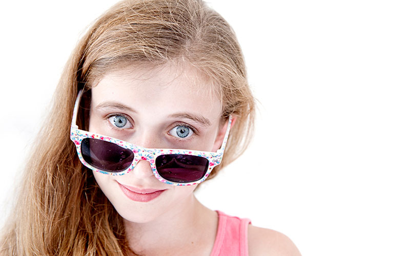 young girl peering over sunglasses